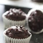 Chocolate protein muffins on the counter top with some in the muffin tin.