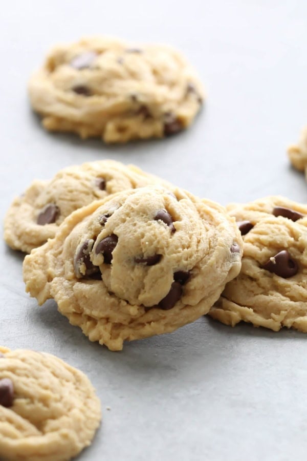 Chocolate Chip Pudding Cookies on a countertop with 1 cookie stacked on some.
