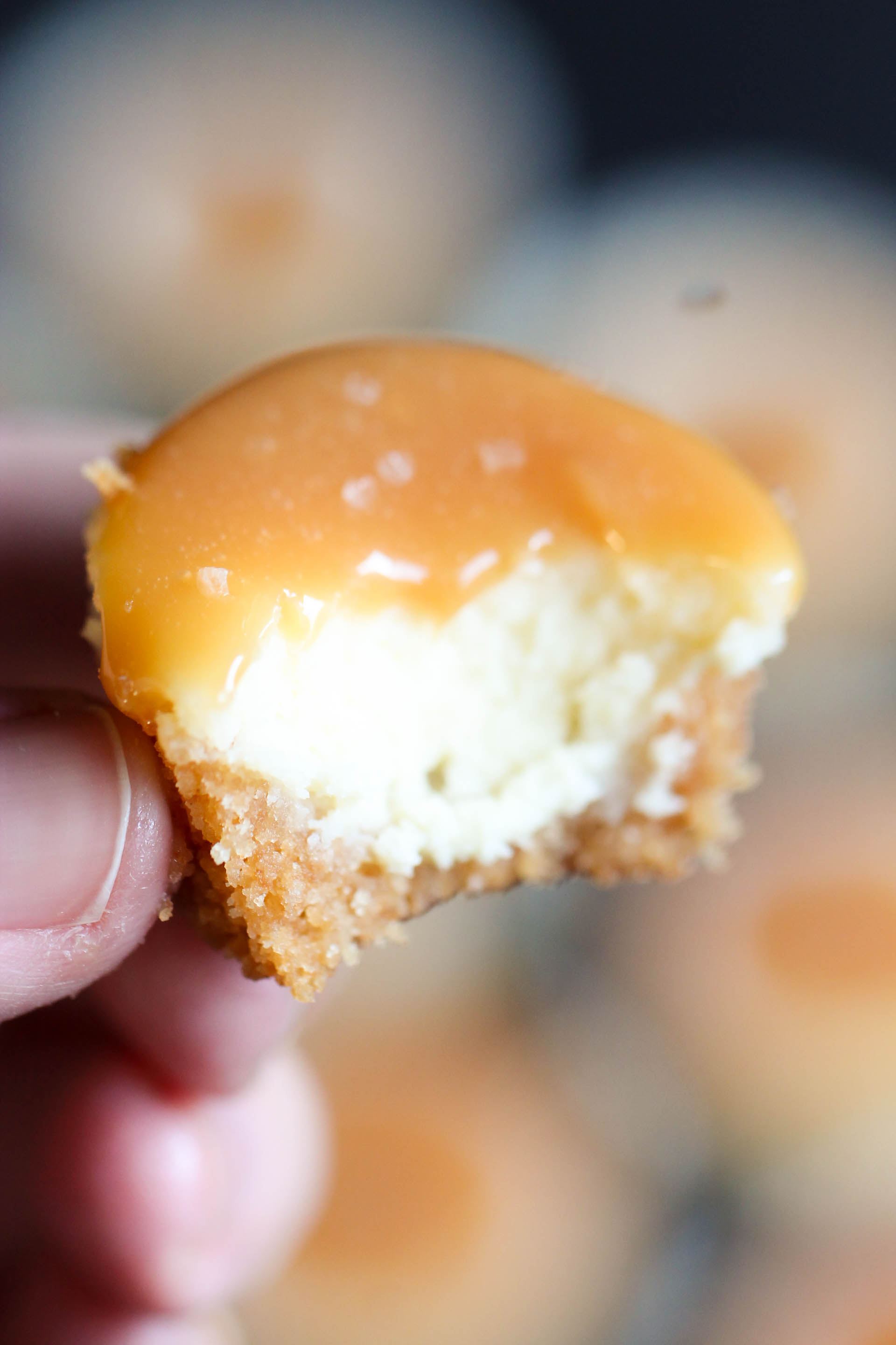 Mini Salted Caramel Cheesecakes with a bite taken out to showcase the creamy insides