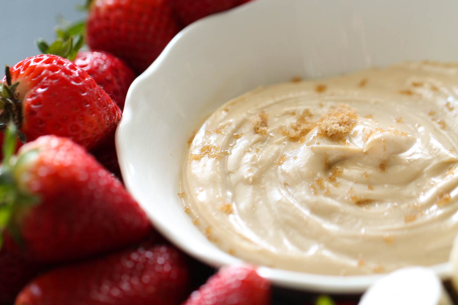 Cream cheese fruit dip with brown sugar in bowl served with strawberries