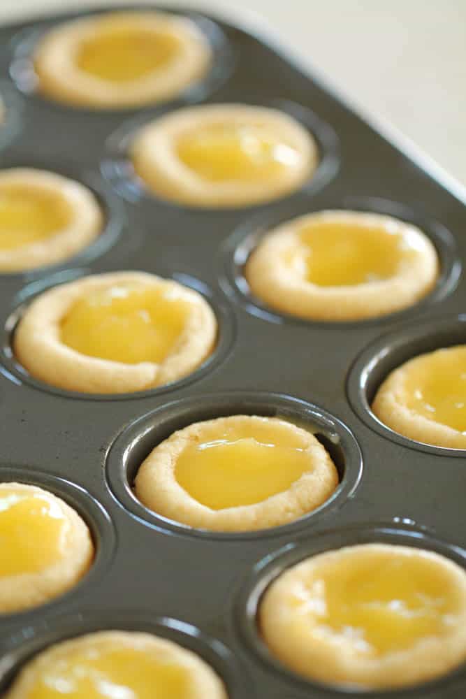 Sugar cookie cups filled with lemon curd in a mini muffin tin.