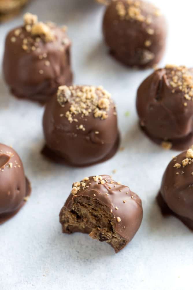 Chocolate Chip Cookie Truffles on a baking sheet lined with parchment paper. One truffle in the front has a bite missing.
