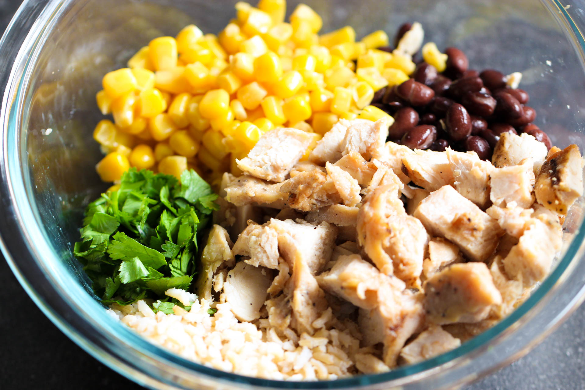 A mixing bowl with rice, chicken, corn, black beans and cilantro
