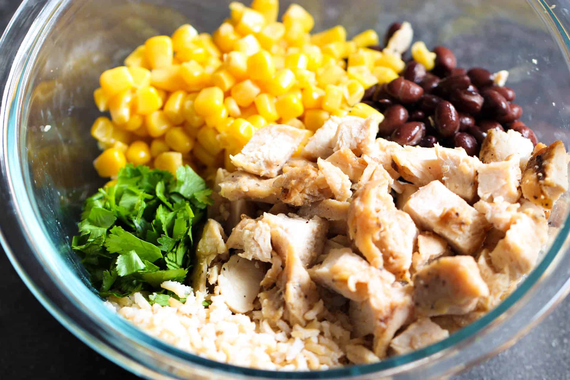 A mixing bowl with rice, chicken, corn, black beans and cilantro