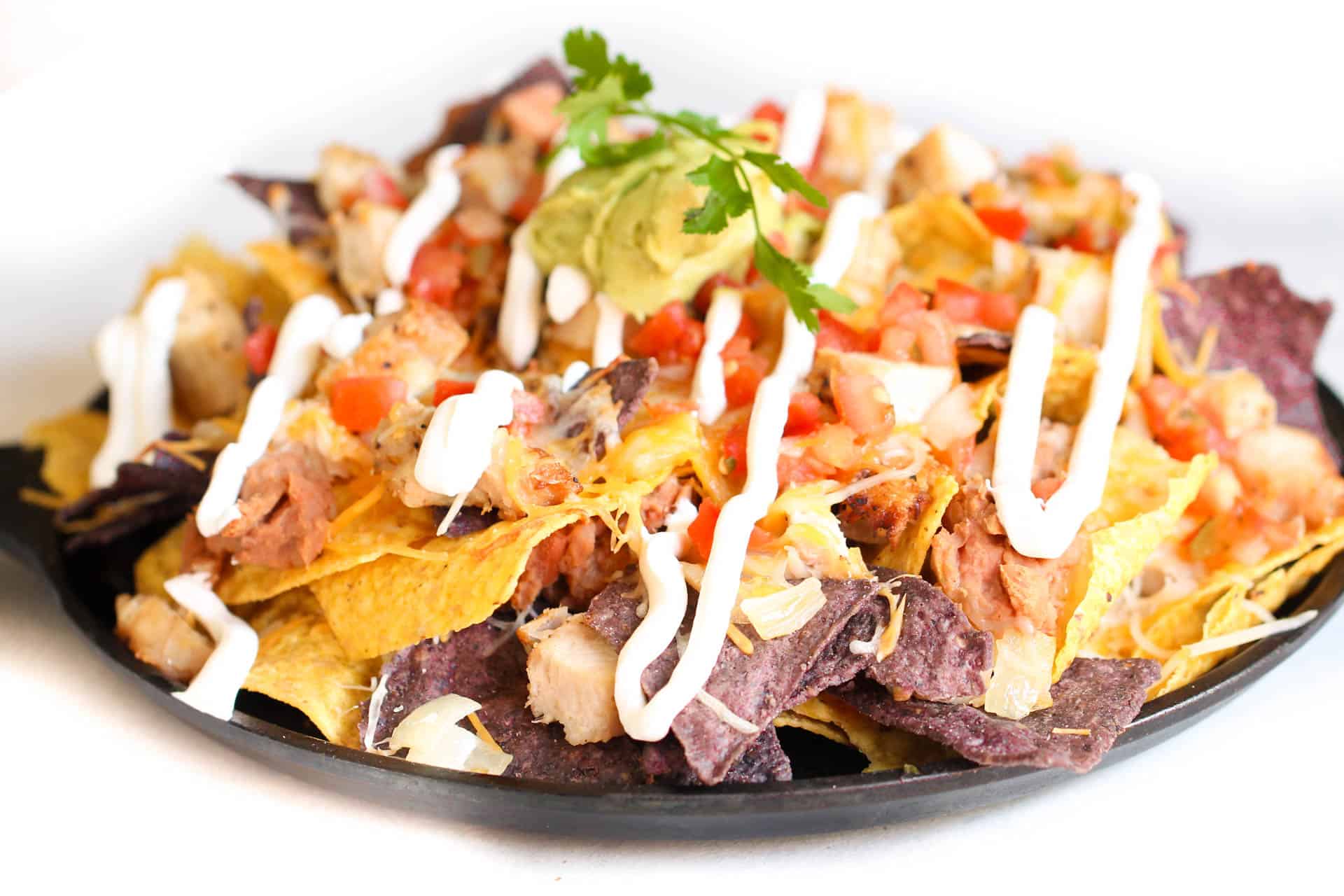 Copycat Fiesta Chicken Nachos on plate with sour cream