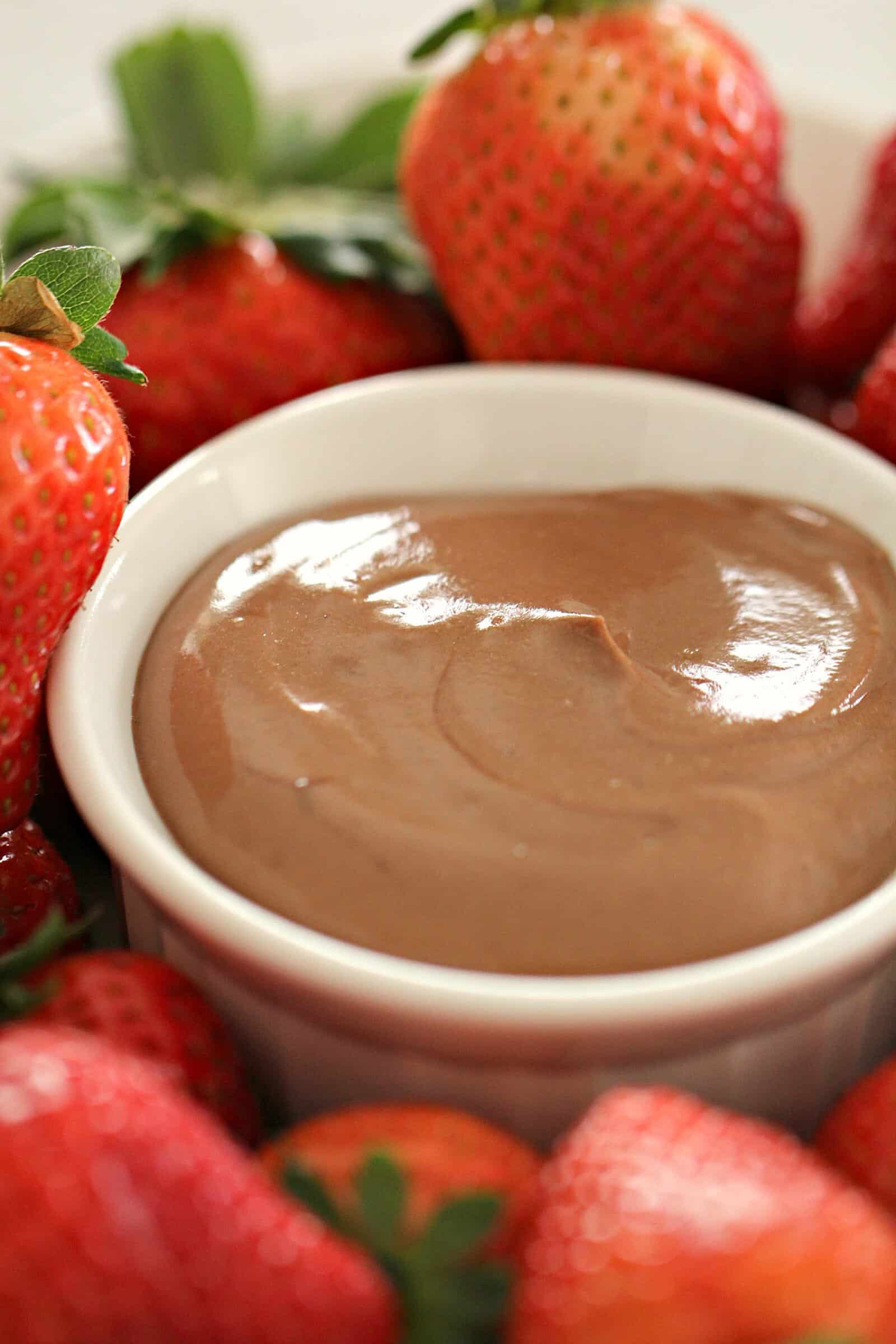 chocolate fruit dip in a white bowl surrounded by strawberries