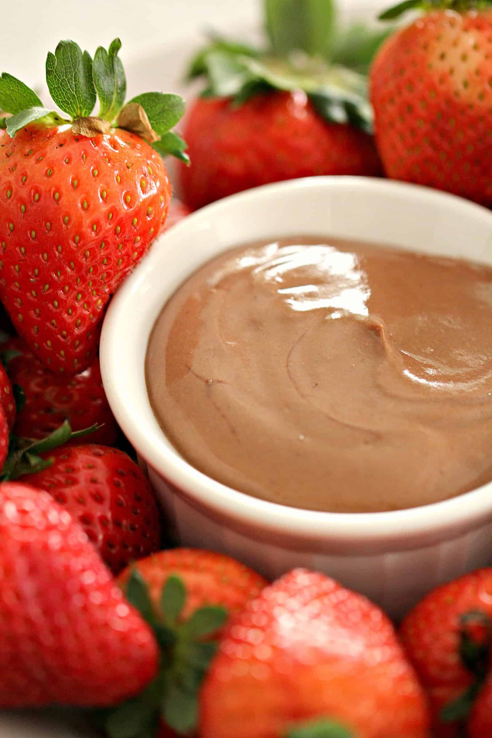 chocolate yogurt fruit dip in a white bowl surrounded by strawberries