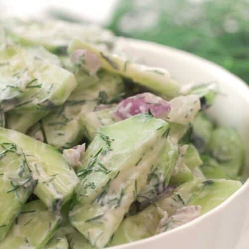 Bowl of creamy cucumber salad with red onions and dill.