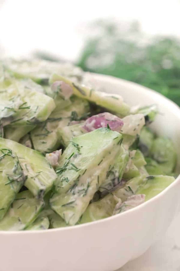 Bowl of creamy cucumber salad with red onions and dill.