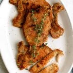 Perfect Fried Pork Chops on a serving platter topped with fresh rosemary