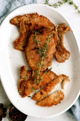 Perfect Fried Pork Chops on a serving platter topped with fresh rosemary