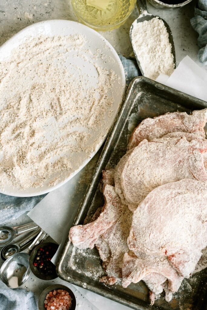 Pork chops are dredged in flour and ready to fry