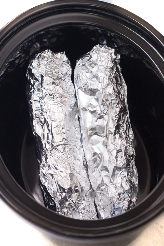 Corn on the cob wrapped in foil in the slow cooker