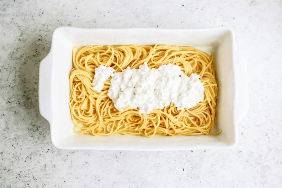 Noodles in the bottom of a casserole dish with cottage cheese mixture spread on top
