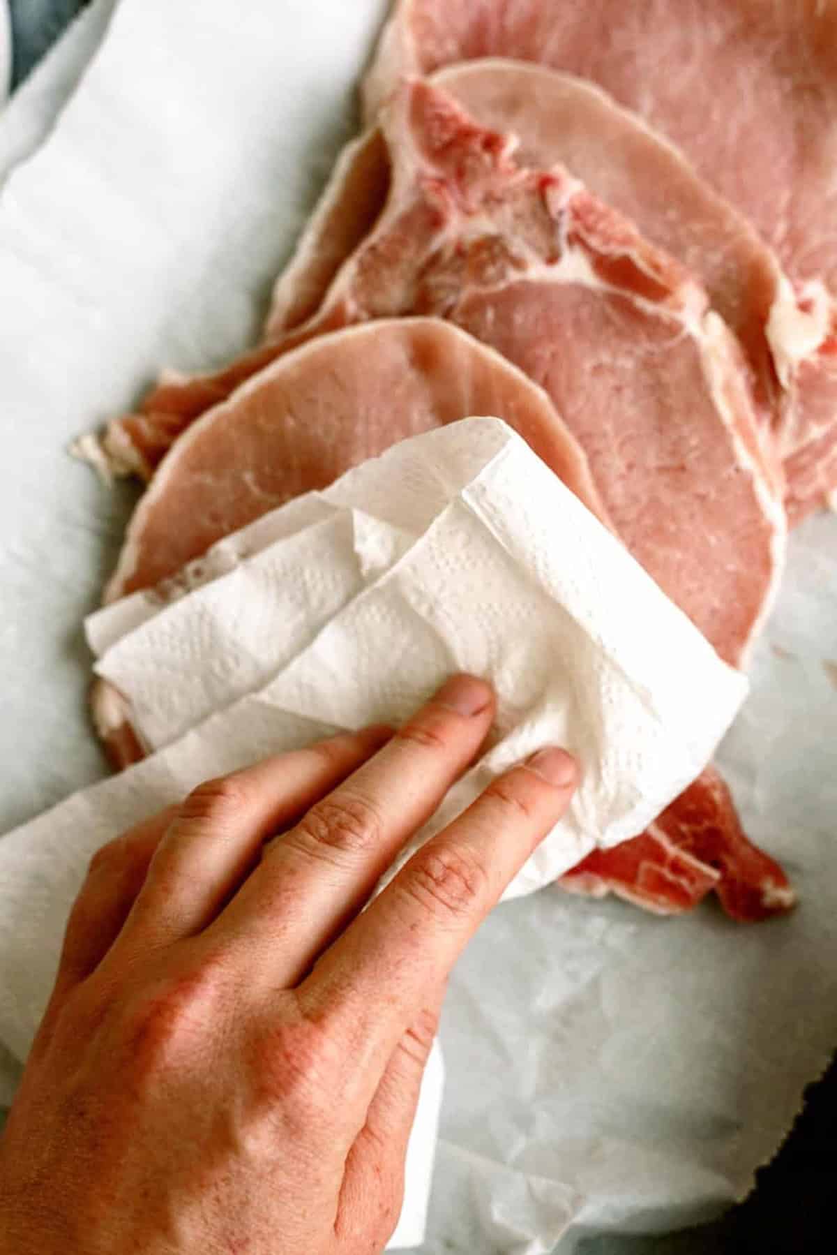 Blotting pork chops dry with a paper towel.