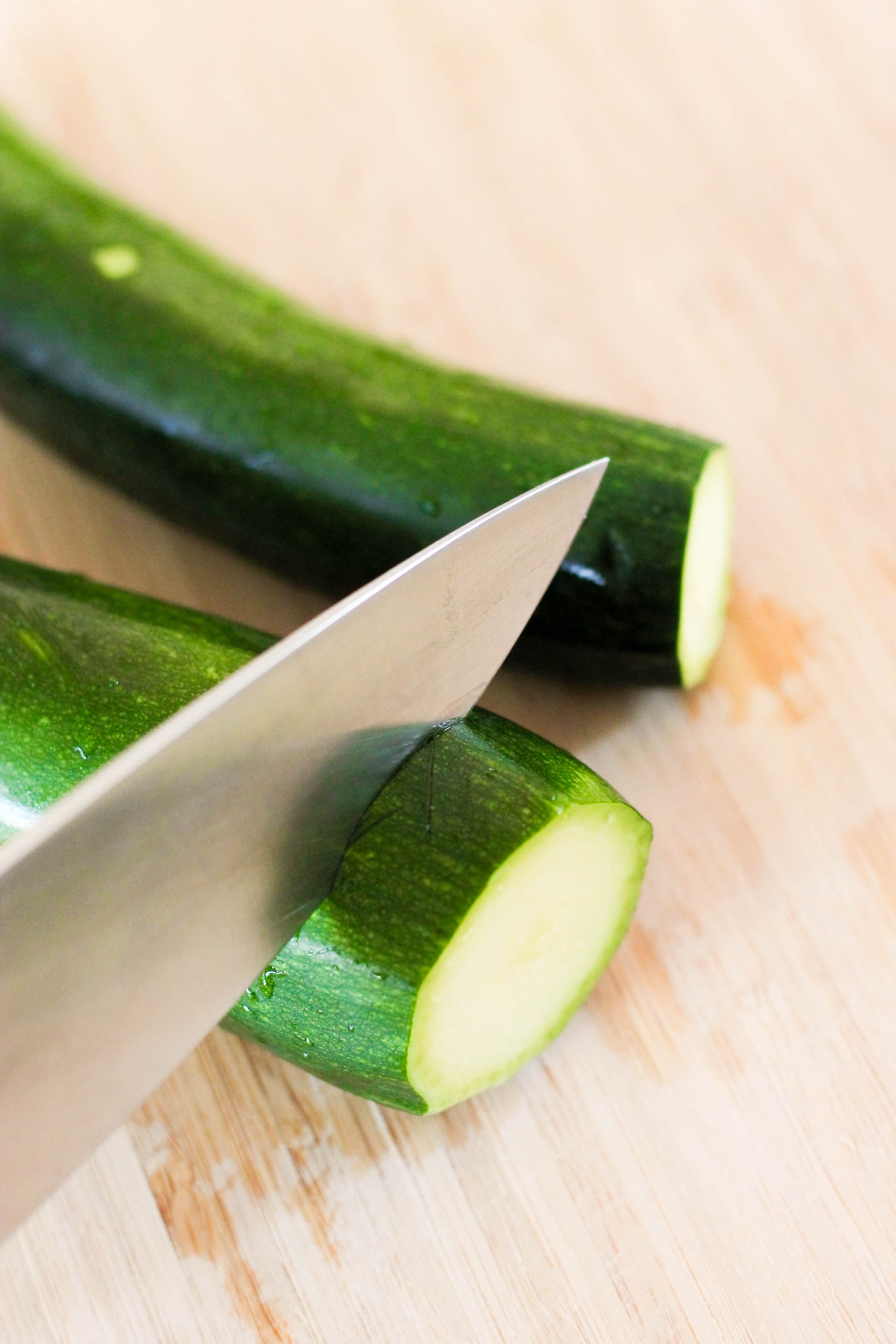 A knife slicing a zucchini