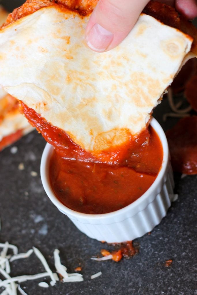 Easy pizza quesadillas being dipped in marinara sauce