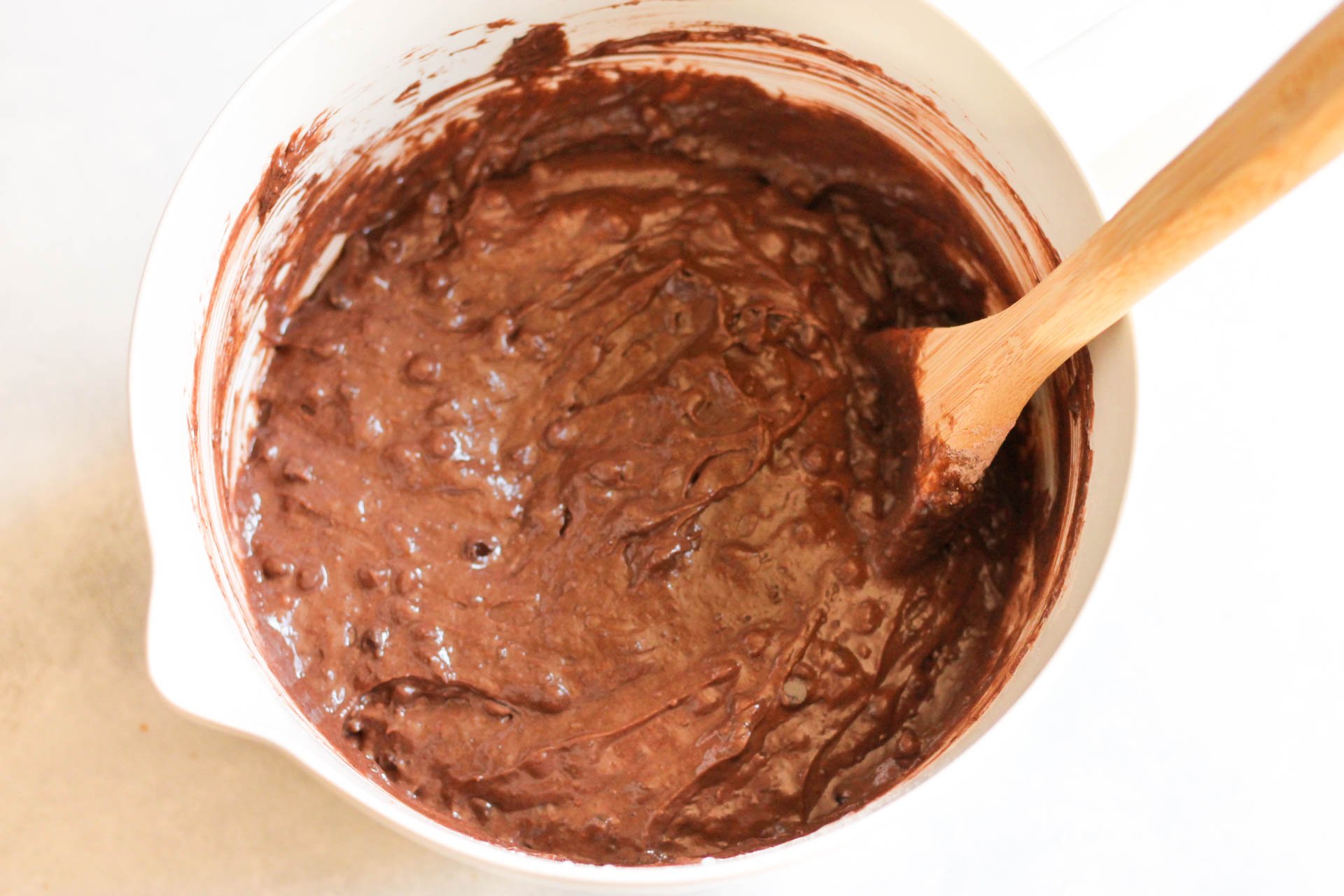 Ingredients for cake mixed together in a bowl with a wooden spoon