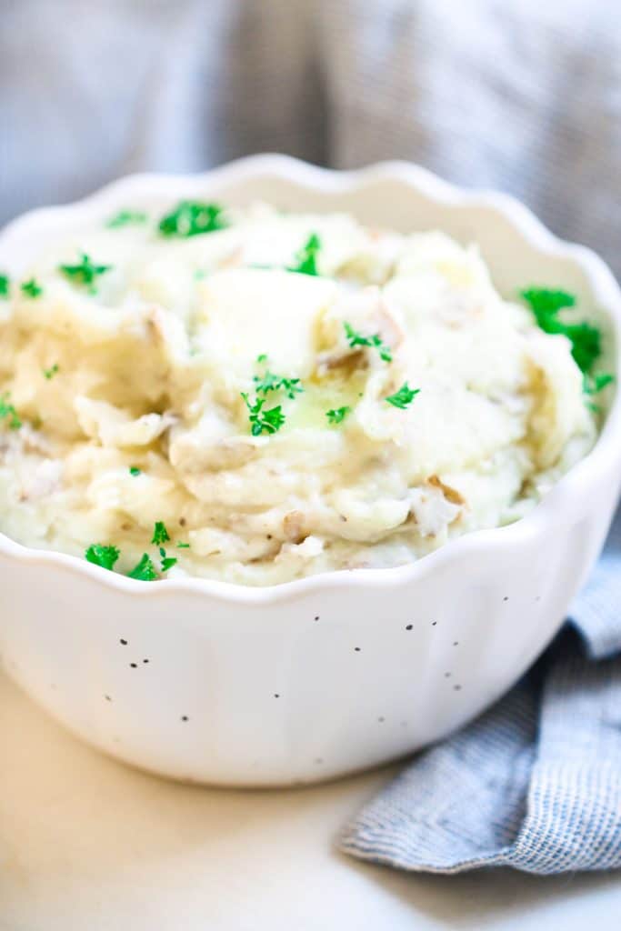 mashed potatoes topped with fresh parsley and butter in a white bowl