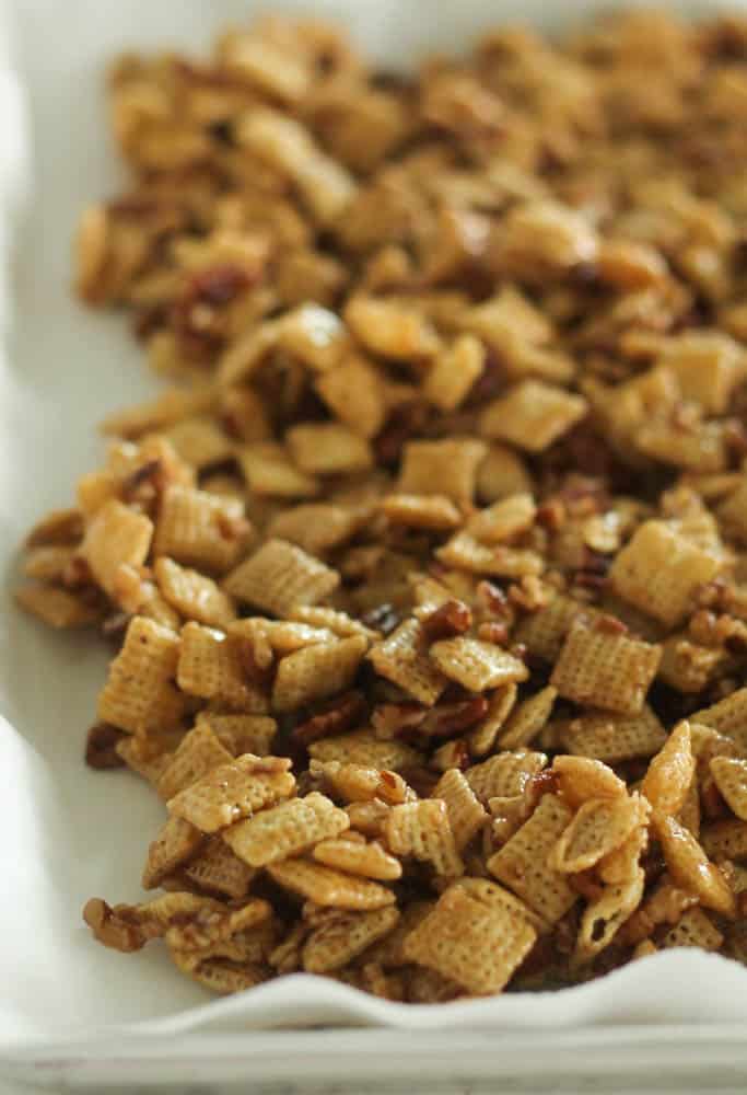 caramel chex mix spread out on a baking sheet covered in wax paper