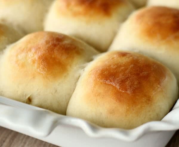 homemade rolls in a white pan with butter on top
