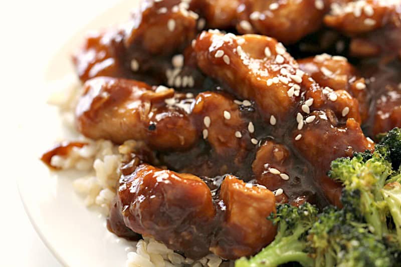 Instant Pot EASY Sesame Chicken and Rice on a white plate sprinkled with sesame seeds