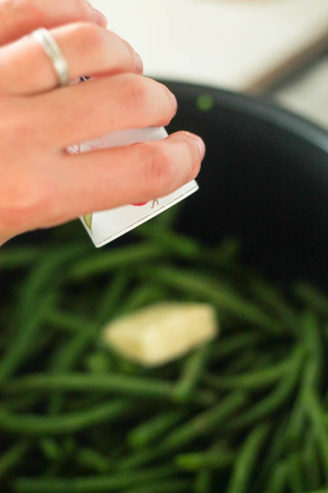 adding pepper and butter to cooked green beans