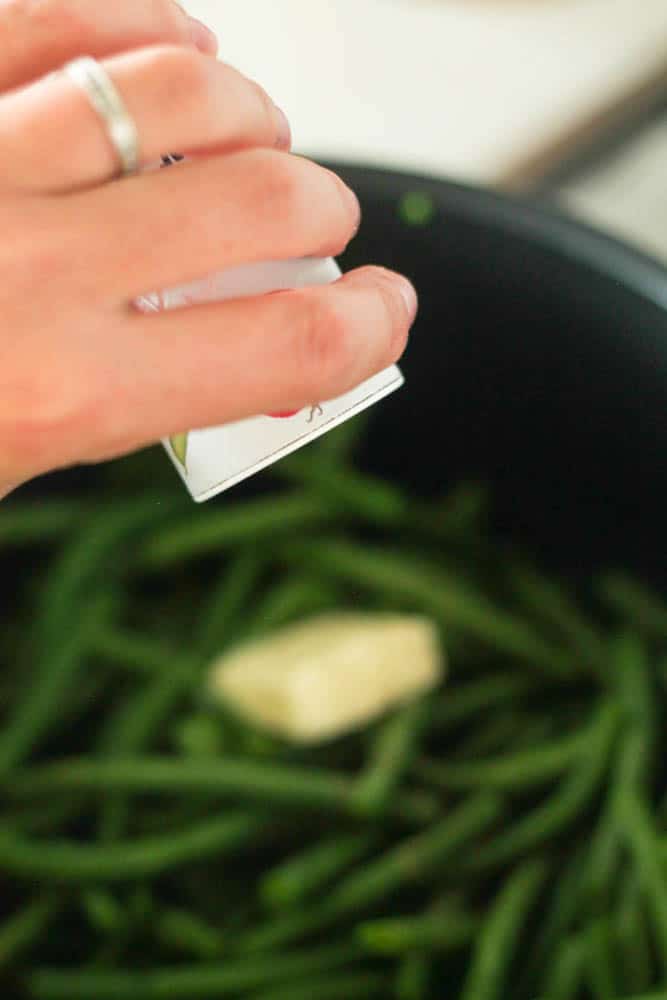 adding pepper and butter to cooked green beans