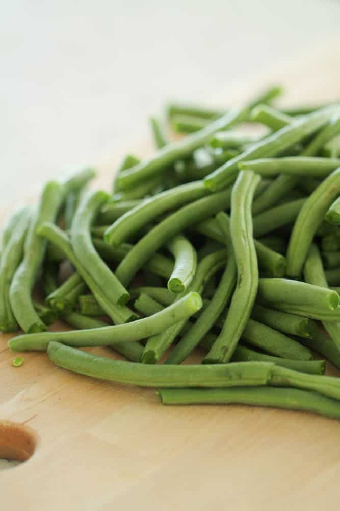 fresh green beans on a cutting board with their ends trimmed off