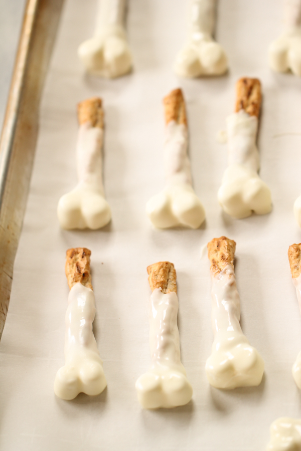 Pretzel rod dipped in white chocolate on a baking sheet