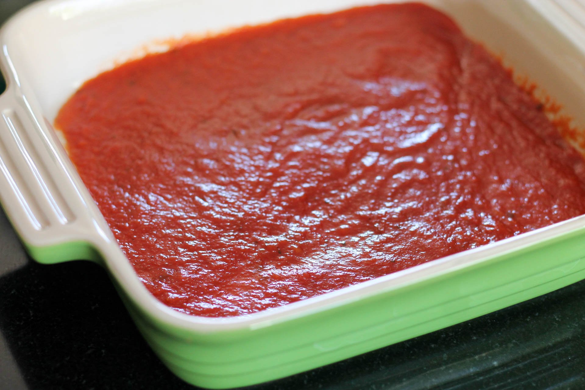 Marinara sauce spread in bottom of pan