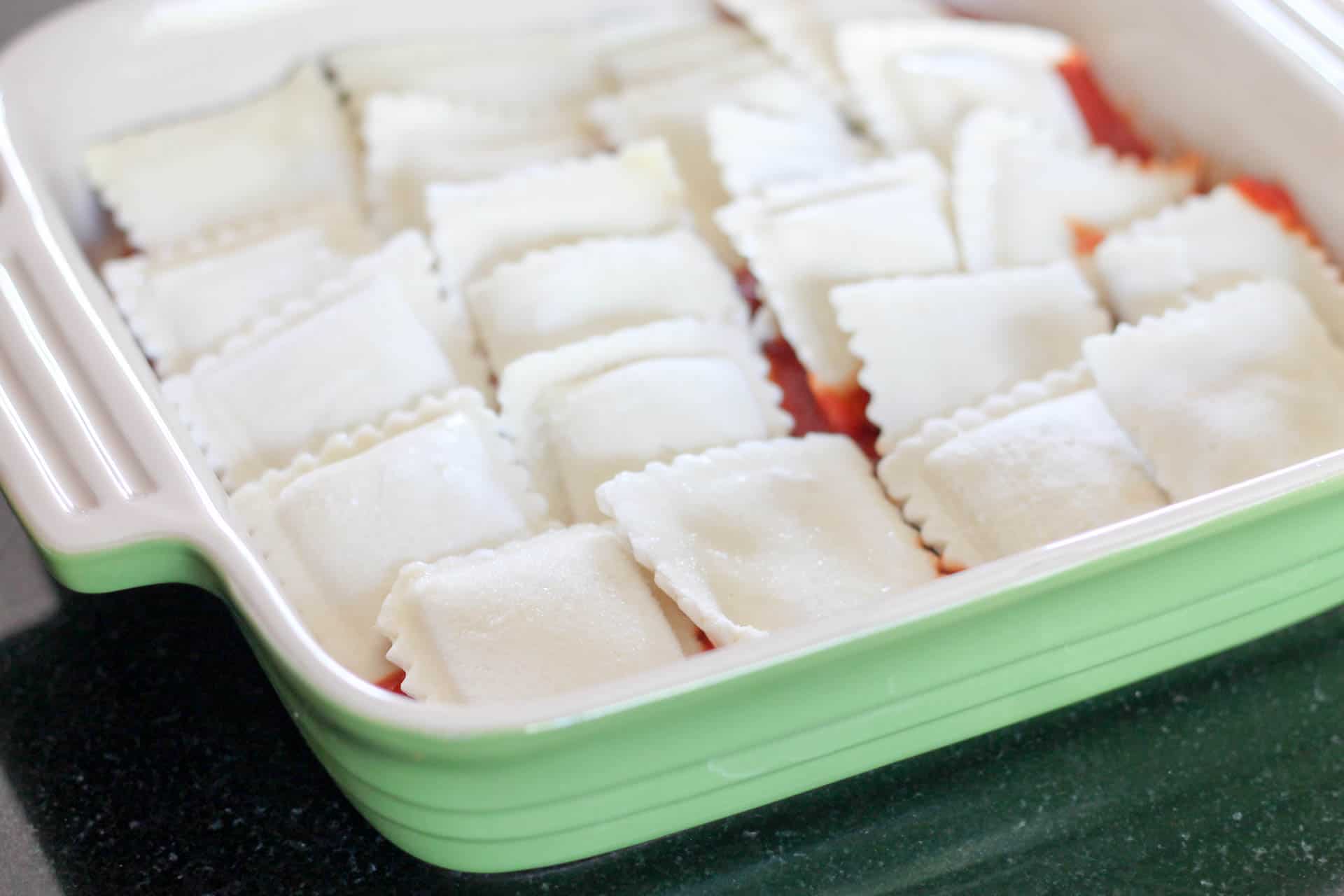 Frozen ravioli on top of marinara sauce in pan