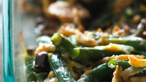 Close-up of a homemade green bean casserole in a glass dish, topped with crispy onions.