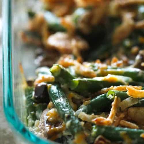 Close-up of a homemade green bean casserole in a glass dish, topped with crispy onions.