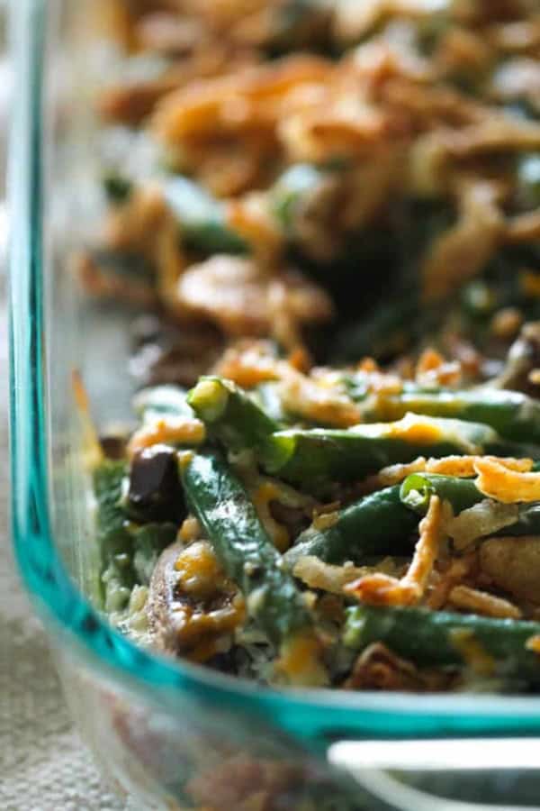 Close-up of a homemade green bean casserole in a glass dish, topped with crispy onions.