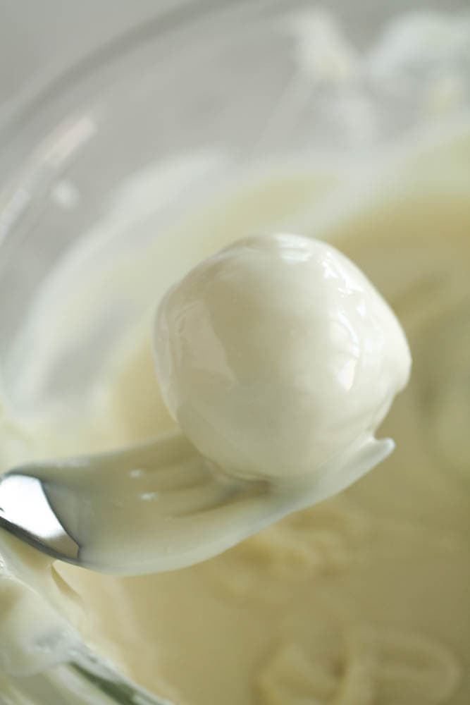 cookie ball dipped in melted white chocolate being held with a fork