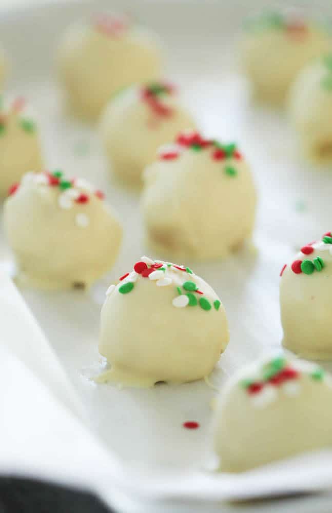 sugar cookie truffles sitting on a baking sheet topped with christmas sprinkles