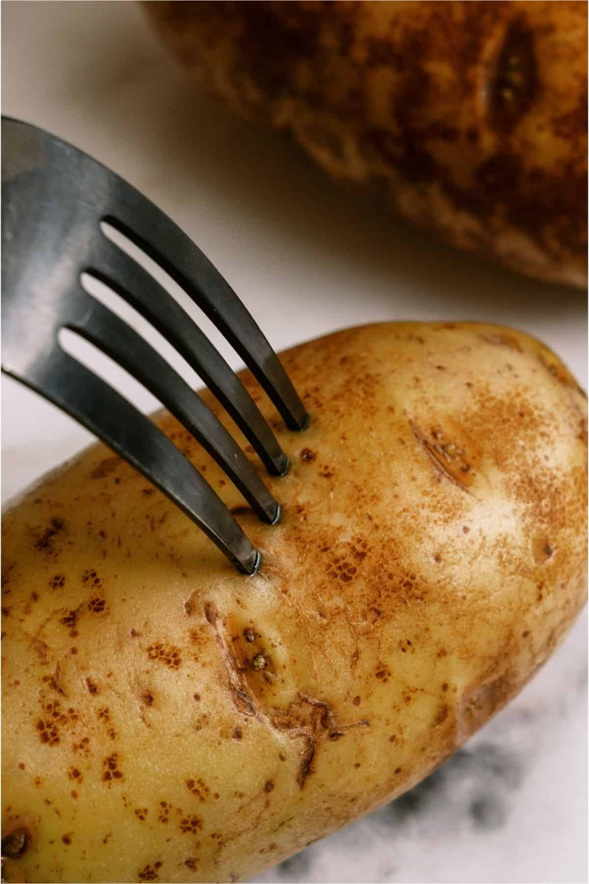 A fork piercing a potato.