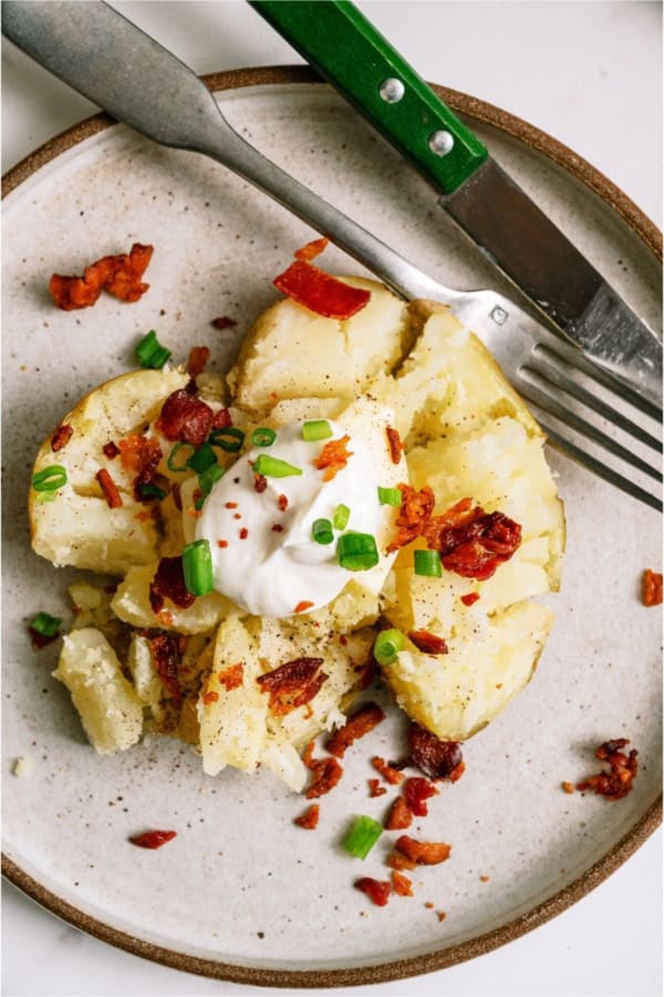 An Instant Pot Baked Potato on a plate with toppings.