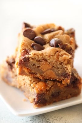 Two stacked pieces of chocolate chip blondies on a white plate.
