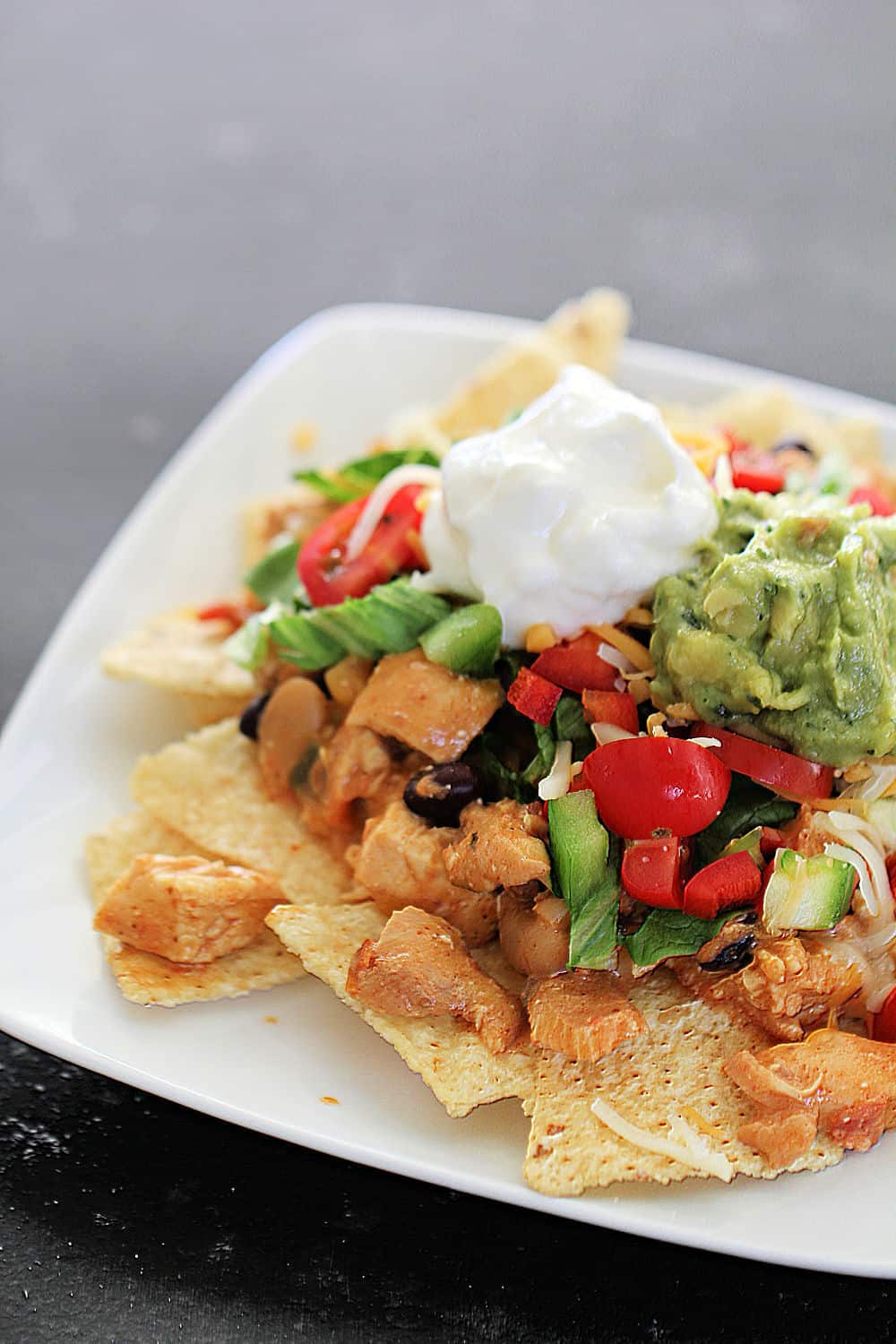 Slow Cooker Creamy Bean and Salsa Chicken on top of tortilla chips on a plate