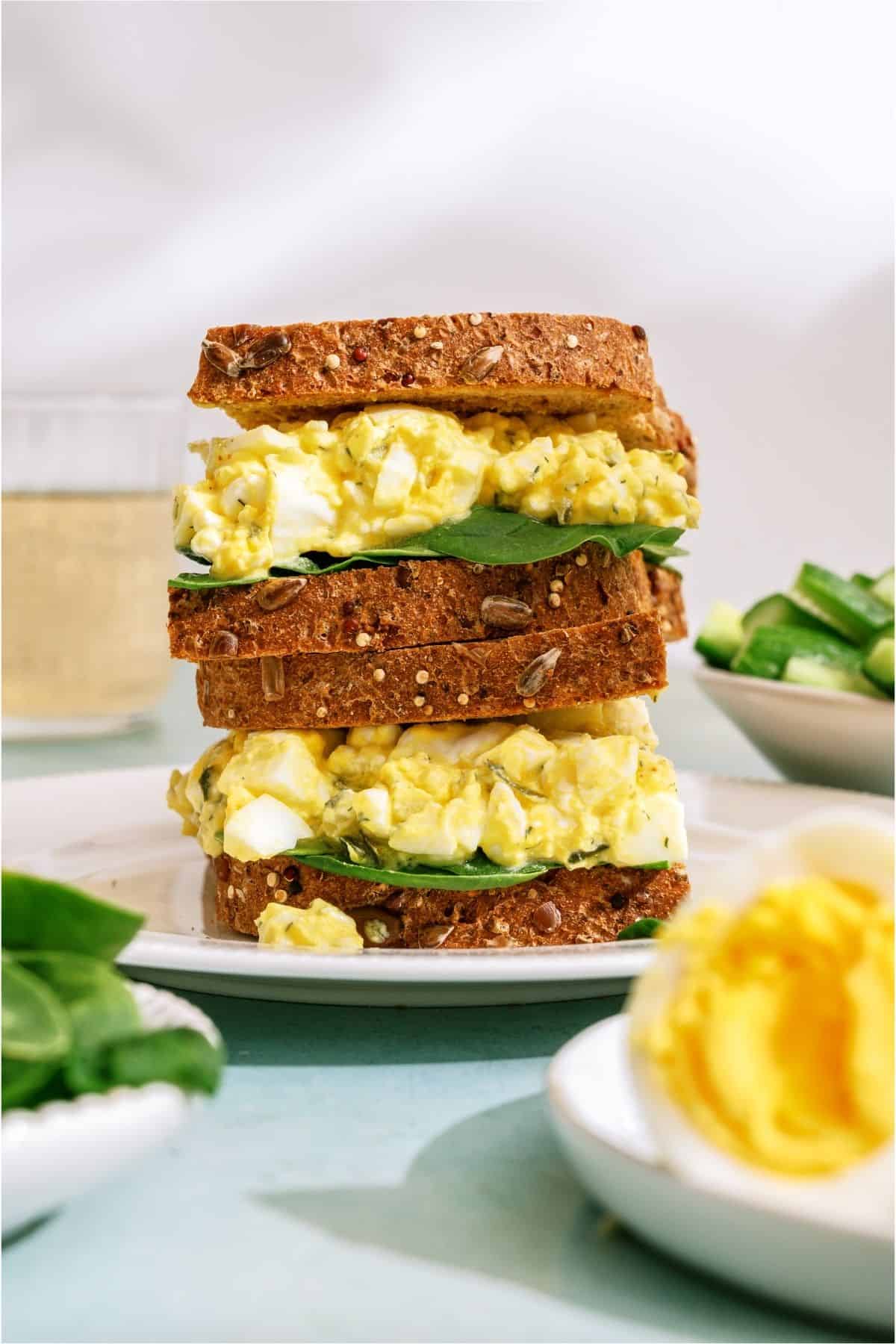 Two High Protein Egg Salad sandwiches stacked on a plate.