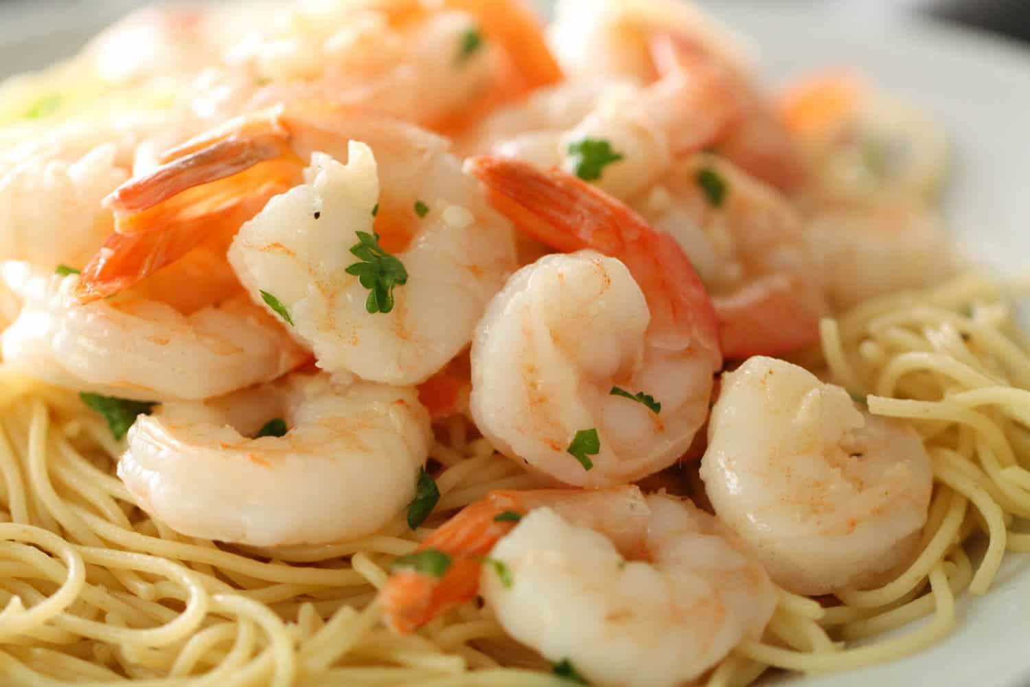 Close up of Easy Lemon Garlic Shrimp served over pasta on a plate