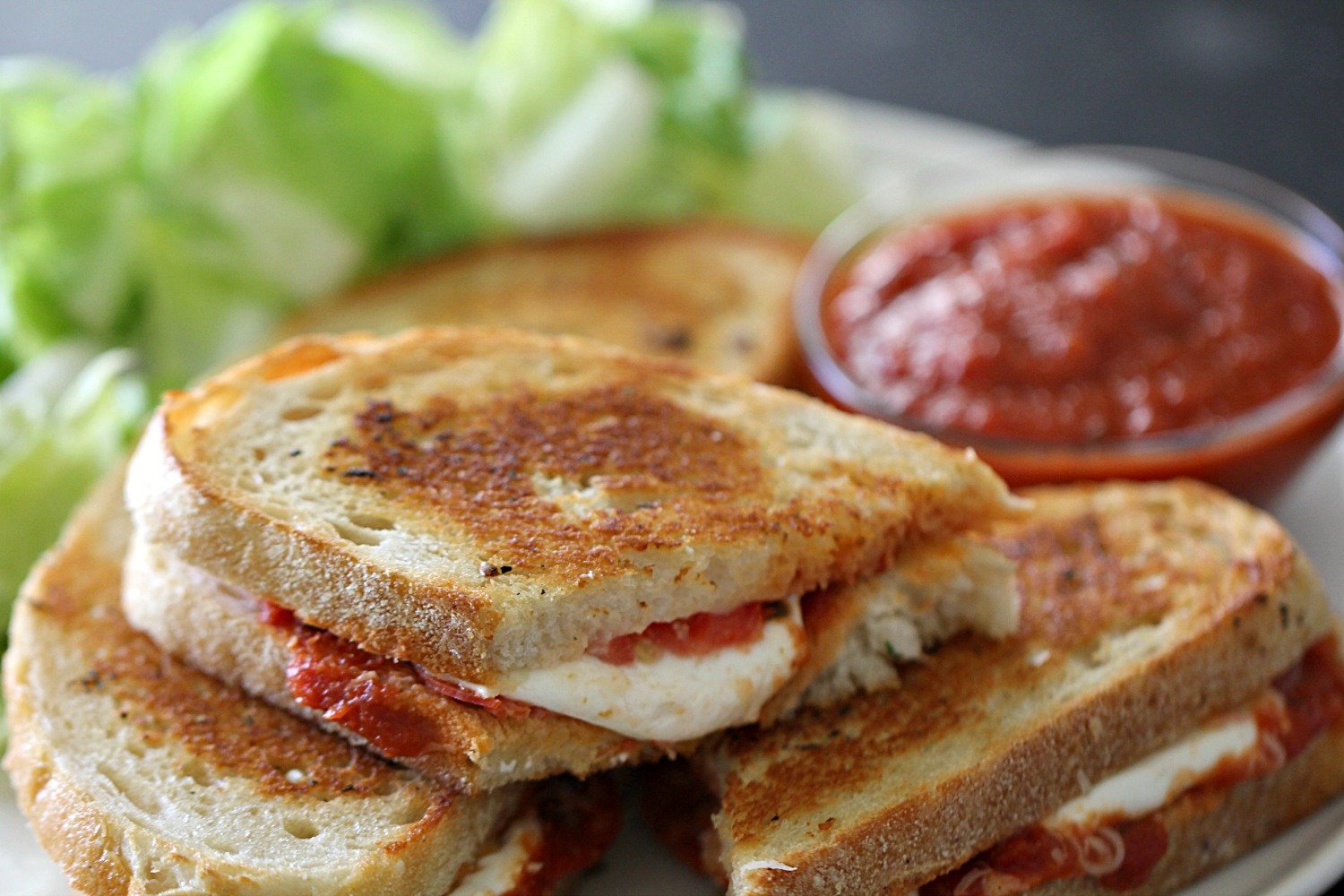 Pepperoni Pizza Grilled Cheese Sandwiches, on plate sliced with salad and dipping sauce