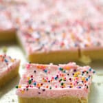 Frosted Sugar Cookie Bars cut into squares and topped with rainbow sprinkles