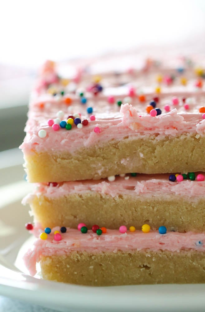 frosted sugar cookie bars stacked on top of each other, cut and ready to eat.