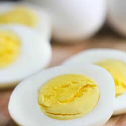 Close-up of sliced hard-boiled eggs on a wooden surface, displaying the yellow yolk and white exterior.