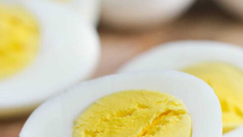 Close-up of sliced hard-boiled eggs on a wooden surface, displaying the yellow yolk and white exterior.