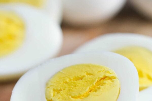 Close-up of sliced hard-boiled eggs on a wooden surface, displaying the yellow yolk and white exterior.