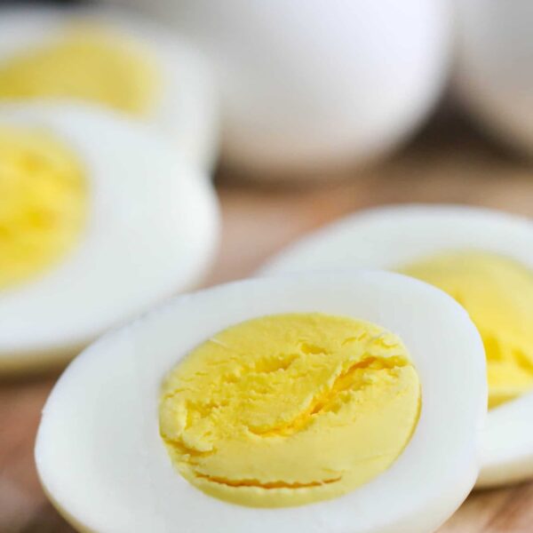 Close-up of sliced hard-boiled eggs on a wooden surface, displaying the yellow yolk and white exterior.